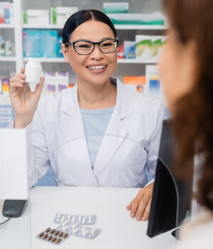 cheerful asian pharmacist holding bottle with medicine