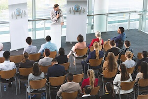 businessman with microphone speaking in front