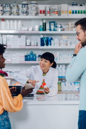 Japanese woman pharmacist selling drugs to a customer in a pharmacy